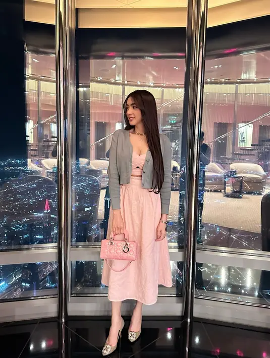 Ia mengenakan strapless cutout midi dress yang dipadukan dengan cardigan abu-abu. [@realangelkaramoy]