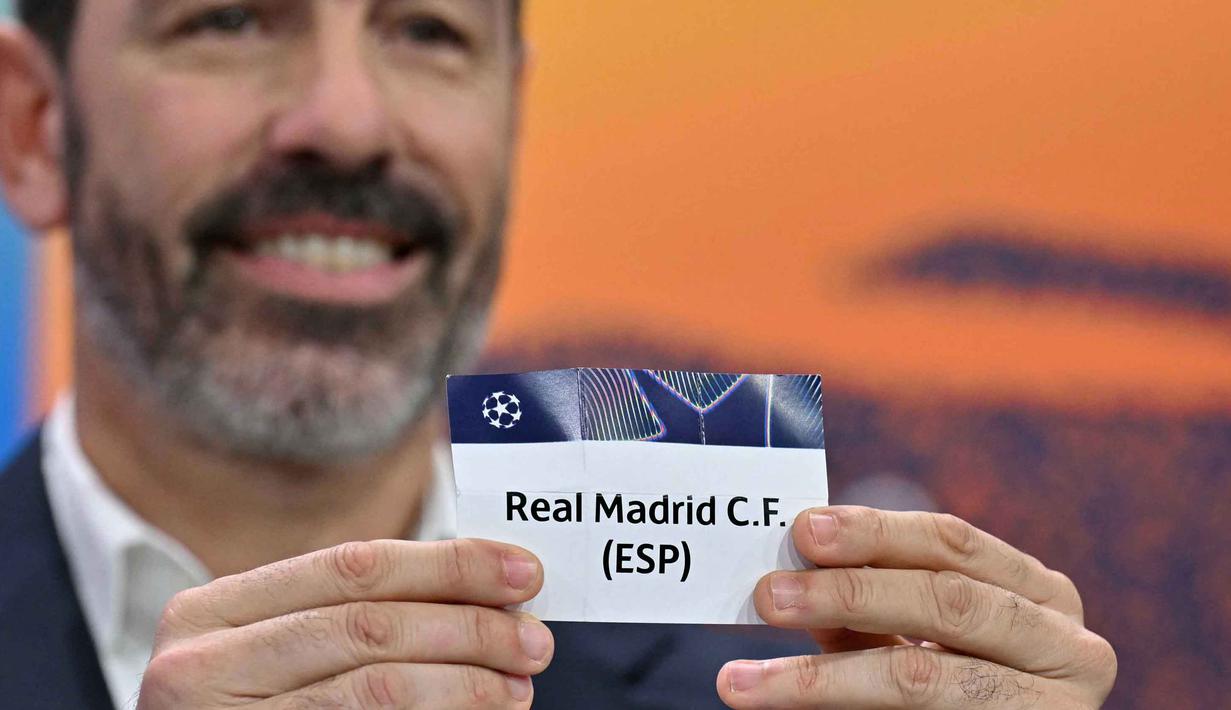 Seperti diketahui, pada pertemuan sebelumnya, Real Madrid harus mengakui keunggulan Benfica dengan skor 2-4. Tampak dalam foto, Mantan pemain sepak bola Prancis dan duta Liga Champions UEFA, Robert Pires, mengangkat slip Real Madrid CF (ESP) selama pengundian babak play-off fase gugur Liga Champions UEFA 2025-2026 di House of European Football, Nyon, Swiss pada 30 Januari 2026. (Harold CUNNINGHAM/AFP)