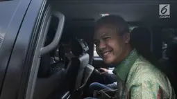 Gubernur Jawa Tengah Ganjar Pranowo tersenyum saat berada di dalam mobil usai diperiksa di gedung KPK, Jakarta, Selasa (4/7). Ganjar Pranowo diperiksa sebagai saksi untuk kasus dugaan korupsi proyek pengadaan e-KTP. (Liputan6.com/Helmi Afandi)