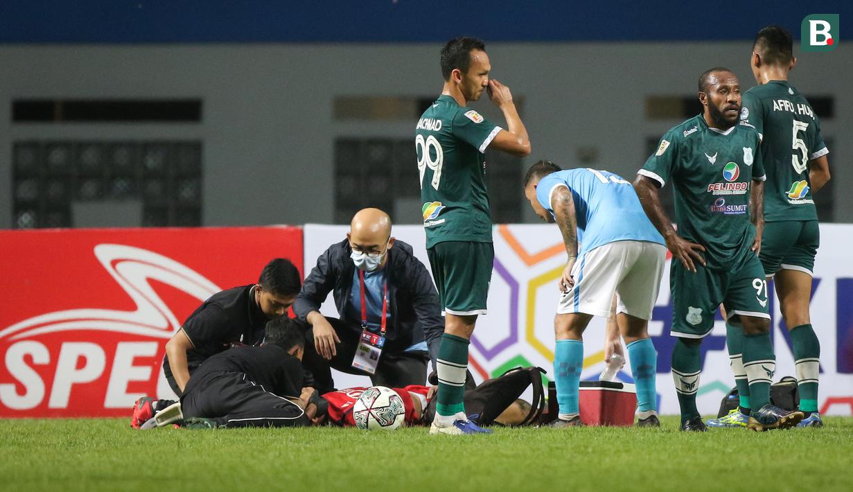 Kiper Sulut United, Fery Bagus Kurniawan mendapatkan perawatan oleh tim medis usai insiden tabrakan dengan pemain PSMS Medan dalam matchday pertama Grup Y Babak 8 Besar Liga 2 2021 di Stadion Wibawa Mukti, Cikarang, Kamis (16/12/2021). (Bola.com/Bagaskara Lazuardi)