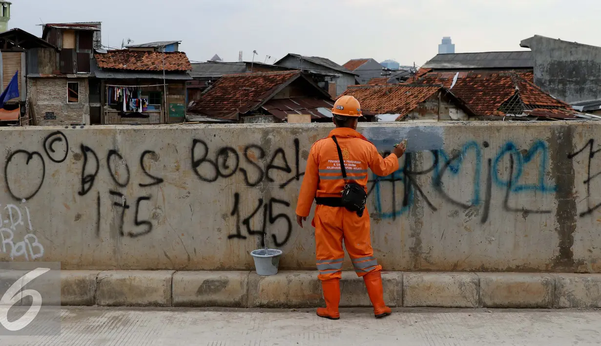 Tembok di sisi tanggul Kali Ciliwung dicat kembali oleh petugas, Jakarta, Selasa (11/10). Aksi vandalisme oleh oknum remaja ini membuat fasilitas publik terlihat kotor. (Liputan6.com/Gempur M Surya)
