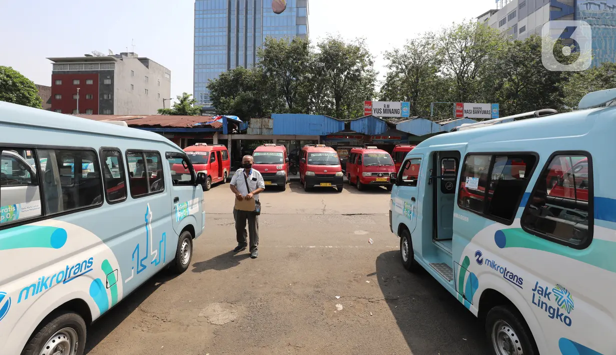 Seorang pria melintasi deretan angkutan kota (angkot) yang terparkir di Terminal Grogol, Jakarta, Sabtu (27/8/2022). Wakil Gubernur DKI Jakarta Ahmad Riza Patria berharap kenaikan tarif ojek online yang dimulai pada 29 Agustus mendatang bisa membuat banyak warga ibu kota beralih ke angkutan umum. (Liputan6.com/Angga Yuniar)