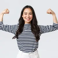 Seorang perempuan berbaju garis hitam putih sedang mengangkat kedua lengannya dengan berpose bisep (Foto Dok: Freepik/benzoix).