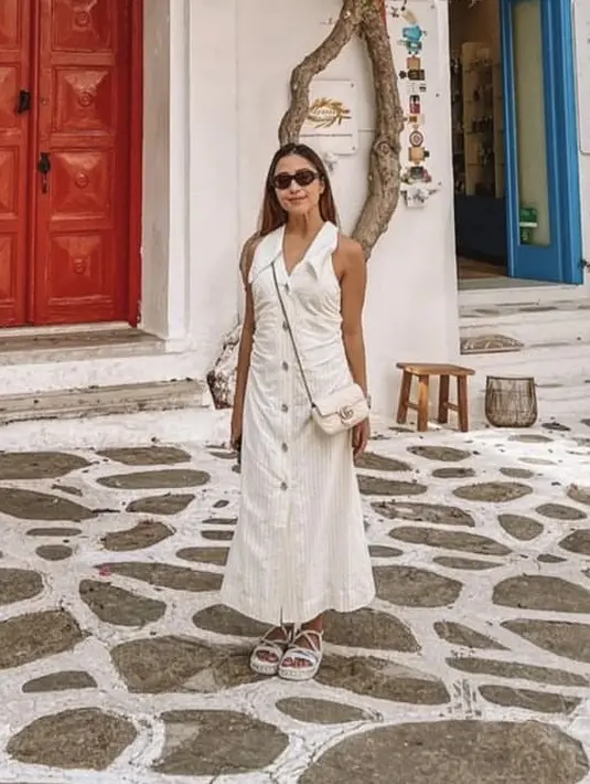 <p>Dress panjang tanpa lengan berdetail kancing warna putih, dipadukan singbag dan sandal warna serasi</p>