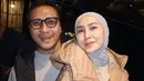 Fenita Arie mengenakan jaket puff coklat muda dipadukan inner kemeja dan kerudung abu-abu. Arie Untung mengenakan vest hitam dipadukan kaos abu-abu. [@ryana_dea]