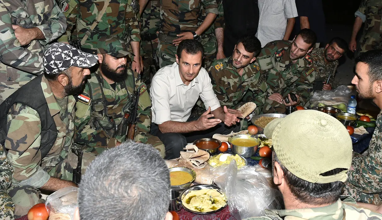 Presiden Suriah Bashar al-Assad (tengah) berbincang saat buka puasa bersama di Desa Marj al-Sultan, timur Ghouta, Damaskus, Suriah, Minggu (26/6).(REUTERS/Sana)