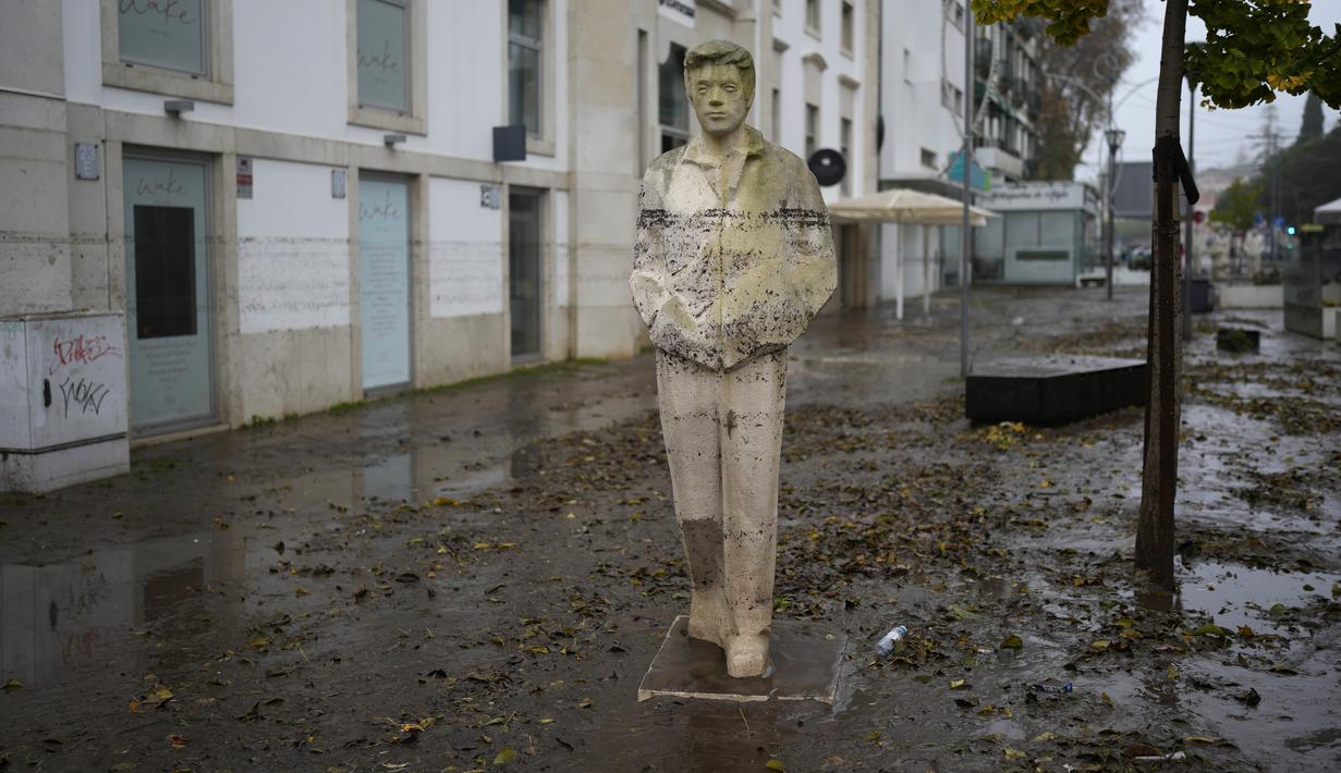 Sebuah patung memiliki tanda ketinggian yang dicapai air ketika jalan dibanjiri semalaman di Alges, tepat di luar Lisbon, Selasa (13/12/2022). Badai Atlantik menghantam semenanjung Iberia, meninggalkan jejak kehancuran pada Selasa, terutama di Ibu kota Portugal,  Lisbon, sebelum pindah ke timur ke Spanyol.  (AP Photo/Armando Franca)