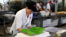 Pembuat kue meletakkan hiasan di atas kue Euro 2016 yang dibuat di sebuah tempat pembuatan kue di Munich, Jerman, Senin (20/6). Beraneka kue bertema Euro 2016 mewarnai perhelatan sepakbola Eropa. (REUTERS/Michaela Rehle)