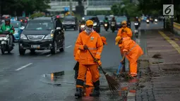 Petugas Dinas Kebersihan membersihkan genangan air usai hujan di kawasan jalan Sudirman, Jakarta, Rabu (22/11). Buruknya sistem drainase membuat petugas membersihkan genangan setiap kali hujan, meski dengan peralatan seadanya. (Liputan6.com/Faizal Fanani)