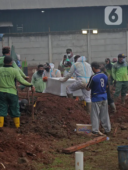 Petugas dengan APD melakukan proses pemakaman dengan protokol Covid-19 di TPU Bambu apus, Jakarta Timur, Minggu (24/1/2021). Pemprov DKI membuka lahan khusus pemakaman jenazah Covid-19 di TPU Bambu Apus dan telah diisi sejak Kamis (21/1/2021) lalu. (Liputan6.com/Herman Zakharia)