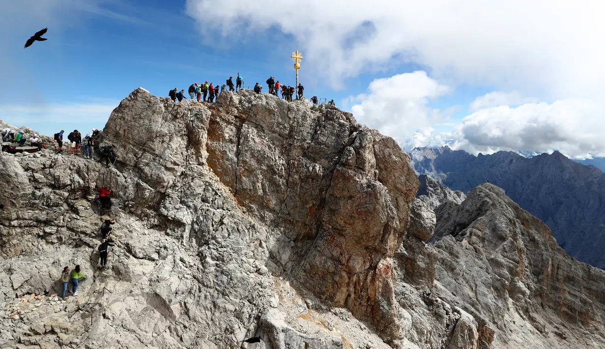 Orang-orang mengantre untuk mencapai puncak salib di puncak gunung tertinggi Jerman, Zugspitze, dekat Garmisch-Partenkirchen, Jerman pada 19 Agustus 2020. Setiap tahunnya gunung dengan ketinggian 2.962 meter tersebut membuat sekitar setengah juta pengunjung terpesona. (AP Photo/Matthias Schrader)