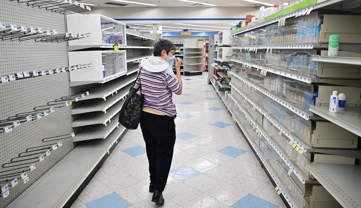 Seorang perempuan melihat-lihat barang apa saja yang tersisa di dekat rak kosong di toko Rite Aid yang akan ditutup Senin depan di Alhambra, California, Rabu (18/10/2023). (Frederic J. BROWN / AFP)