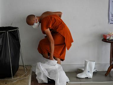 Seorang biksu melepas alat pelindung diri setelah melakukan kremasi untuk korban virus corona COVID-19 di Wat Chin Wararam Worawihan, Bangkok, Thailand, 30 Juli 2021. Kasus COVID-19 di Thailand kini tengah melonjak. (Lillian SUWANRUMPHA/AFP)
