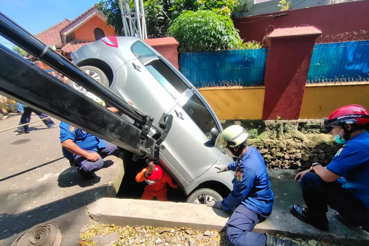 Petugas Damkar mengevakuasi mobil yang terpersok ke selokan di Jalan Pembaharuan, Kelapa Dua Wetan, Ciracas, Jakarta Timur