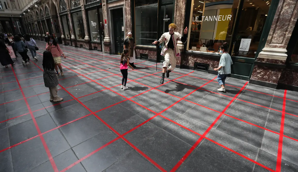 Seorang seniman memainkan permainan dalam garis persegi (grid game) dengan anak-anak di Royal Gallery of Saint Hubert di Brussel, Belgia (15/7/2020). Permainan ini dirancang agar orang menghormati aturan jaga jarak sosial selama pandemi COVID-19. (Xinhua/Zheng Huansong)