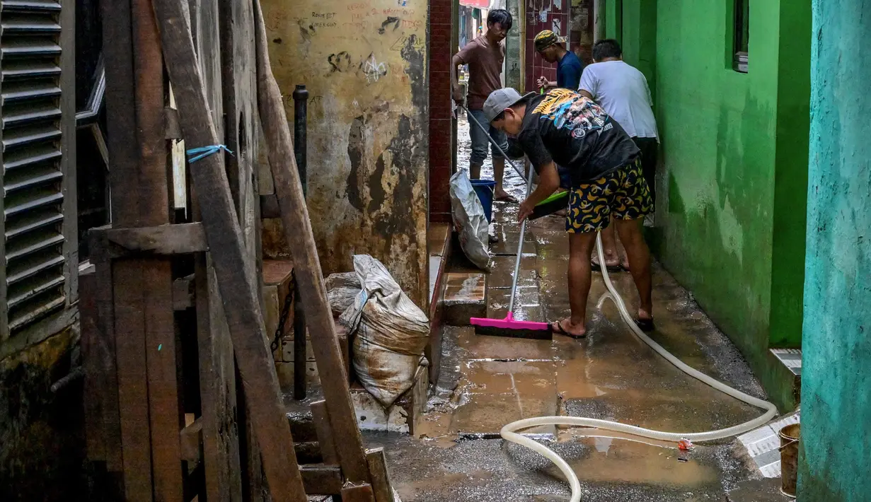 Warga membersihkan jalan di depan rumah mereka nan dipenuhi lumpur setelah banjir melanda lingkungan mereka setelah hujan deras di Jakarta pada Senin 7 Juli 2025. (BAY ISMOYO/AFP)