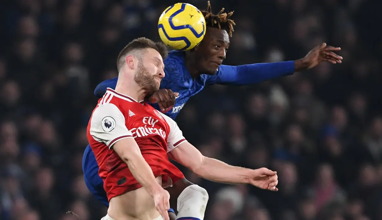 Bek Arsenal, Shkodran Mustafi berebut bola dengan striker Chelsea, Tammy Abraham pada lanjutan pertandingan Liga Inggris di Stamford Bridge, Selasa (21/1/2020). Chelsea gagal memetik hasil maksimal usai ditahan Arsenal dengan skor 2-2. (DANIEL LEAL-OLIVAS / AFP)