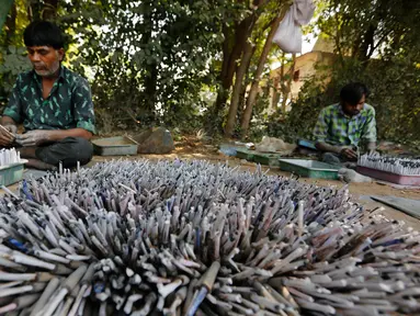 Pekerja membuat petasan untuk festival Diwali atau Dipavali bagi umat Hindu yang akan datang, di sebuah pabrik pinggiran  Ahmadabad, Senin (22/10). Permintaan petasan di India semakin meningkat jelang perayaan Festival "Cahaya" Diwali. (AP/Ajit Solanki)