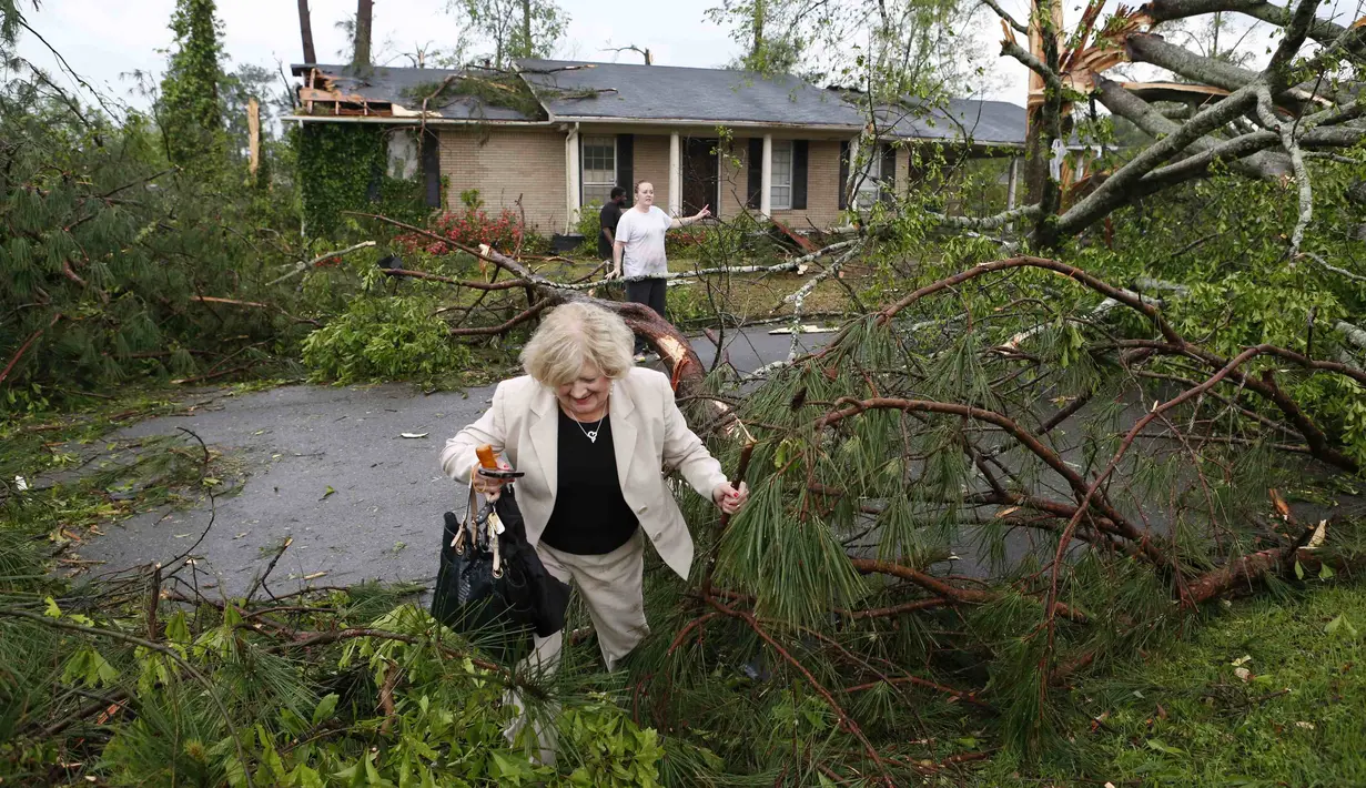 Seorang nenek terlihat melewati pohon-pohon tumbang untuk masuk ke rumahnya setelah tornado menerjang beberapa kota di selatan Amerika Serikat, Senin, (28/4/14). (REUTERS/Thomas Wells)
