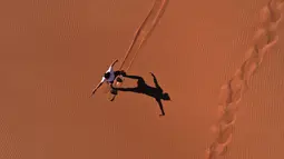 Aksi turis bermain sandboarding (papan seluncur) di gurun Dubai pada 11 Januari 2021. Di sini para wisatawan dapat mencoba sensasi bermain sandboarding sambil memandang hamparan lautan pasir cokelat. (Photo by GIUSEPPE CACACE / AFP)