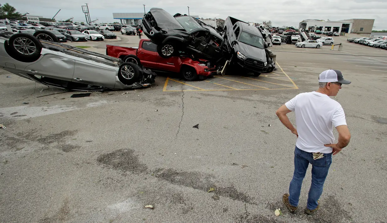 Seorang pekerja melihat-lihat mobil yang rusak akibat tornado di sebuah dealer di Jefferson City, Missouri, AS, Kamis (23/5/2019). Tornado juga menghantam ibu kota negara bagian, membawa hujan lebat, hujan es, angin, dan kilat. (AP Photo/Charlie Riedel)