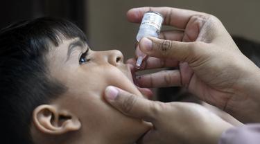 Petugas kesehatan memberikan vaksin polio kepada seorang anak selama kampanye vaksinasi polio dari pintu ke pintu di daerah kumuh di Karachi, Paksistan, Senin (23/5/2022). Pakistan meluncurkan upaya anti-polio baru pada hari Senin, lebih dari seminggu setelah pejabat mendeteksi kasus ketiga tahun ini di wilayah barat laut negara itu yang berbatasan dengan Afghanistan. (Asif HASSAN / AFP)