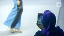 Pengunjung mengambil gambar model yang sedang memeragakan busana dalam Muslim Fashion Festival (Muffest) 2020 di Jakarta Convention Center (JCC), Jakarta, Kamis (20/2/2020). Muffest 2020 ajang pameran para pelaku industri busana muslim Tanah Air. (merdeka.com/Imam Buhori)