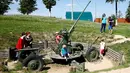Pengunjung bermain menikmati alat-alat tempur yang pernah digunakan dalam Perang Dunia II di Memorial "Stalin Line", dekat Desa Goroshki, Belarusia, (10/9). (Reuters/Vasily Fedosenko)