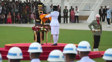 Presiden Joko Widodo (kiri tengah) menyerahkan bendera Merah-Putih kepada seorang pembawa bendera untuk dikibarkan dalam upacara Peringatan Kemerdekaan ke-79 Republik Indonesia di Istana Kepresidenan yang baru di Ibu Kota Negara, Nusantara, Sabtu, 17 Agustus 2024. (AP Photo/Achmad Ibrahim)