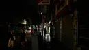 Saat ini, warga Kairo, Mesir, dipaksa untuk menyesuaikan diri dengan kota yang lebih gelap dan sepi demi menjaga ketahanan energi nasional. Tampak dalam foto, orang-orang berjalan melewati toko-toko yang tutup lebih awal karena jam malam yang diberlakukan pemerintah untuk mengurangi biaya energi di pusat kota Kairo, Mesir, pada Kamis 2 April 2026. (Khaled DESOUKI/AFP)