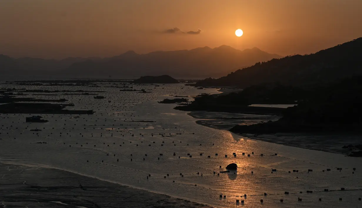Matahari terbenam terlihat dari Pulau Dong An di Xiapu, Provinsi Fujian, China, Kamis (12/12/2019). Xiapu menjadi daya tarik tersendiri bagi fotografer pemula karena jauh dari gedung pencakar langit dan hiruk pikuk kota-kota besar di China. (RETAMAL HECTOR/AFP)