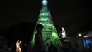 Seorang pemain sulap bermain dengan api saat menghadiri upacara penyalaan pohon Natal yang terbuat dari botol plastik daur ulang di Caracas, Venezuela, Selasa (13/12/2022). Pohon Natal yang dibuat dari sekitar 15.000 botol plastik daur ulang ini diinisiasi oleh organisasi nirlaba dan non-pemerintah Oko Spire dan kolaborator. (Yuri CORTEZ / AFP)