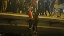 Demonstran menuruni jembatan menggunakan tali untuk melarikan diri dari Universitas Politeknik Hong Kong di Distrik Hung Hom, Hong Kong, Senin (18/11/2019). Lusinan demonstran melarikan diri dari Universitas Politeknik Hong Kong yang dikepung polisi selama berhari-hari. (ANTHONY WALLACE/AFP)