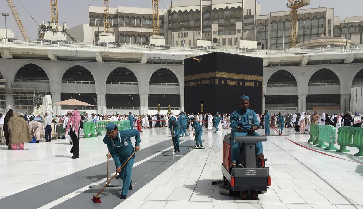 Para pekerja membersihkan Masjidil Haram saat kegiatan umrah di kota suci Muslim Mekah, Arab Saudi, Senin, (2/3/2020). Semenjak pemerintah Arab Saudi melarang kegiatan umrah, tempat paling suci umat Islam ini menjadi terlihat lebih sepi dari biasanya. (AP Photo/Amr Nabil)