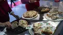 Relawan mengantarkan potongan pizza yang dibuat oleh master pizza selama Kejuaraan Pizza Argentina di Buenos Aires, Argentina, Selasa (7/6/2022). Pemenang yang terpilih sebagai “Great Argentine Champion” akan menjadi bagian dari tim Argentina di Kejuaraan Pizza Dunia 2023 di Parma (Italia). (AP Photo/Rodrigo Abd)