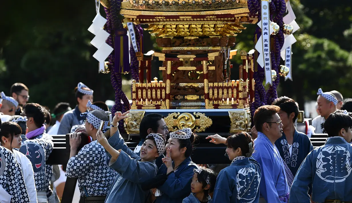 Dua wanita berselfie saat mengikuti perayaan nasional untuk menandai penobatan Kaisar Jepang Naruhito di depan Istana Kekaisaran di Tokyo (9/11/2019). Kaisar Naruhito menjalankan ritual penobatannya setelah dilantik pada 1 Mei 2019. (AFP Photo/Charly Triballeau)