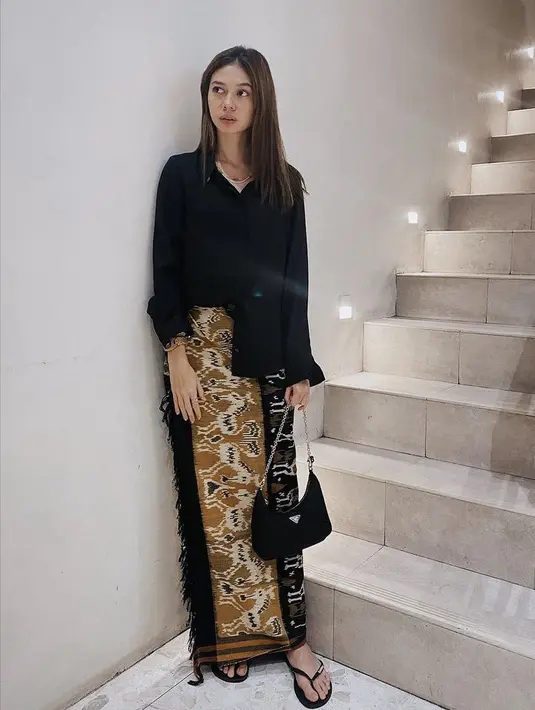 Yuki Kato tampil dengan kemeja hitam yang dipadukan kain lilit motif khas nusantara. Gaya ini cocok dikenakan saat lebaran hingga halal bihalal. Credit: Instagram (@yukikt)