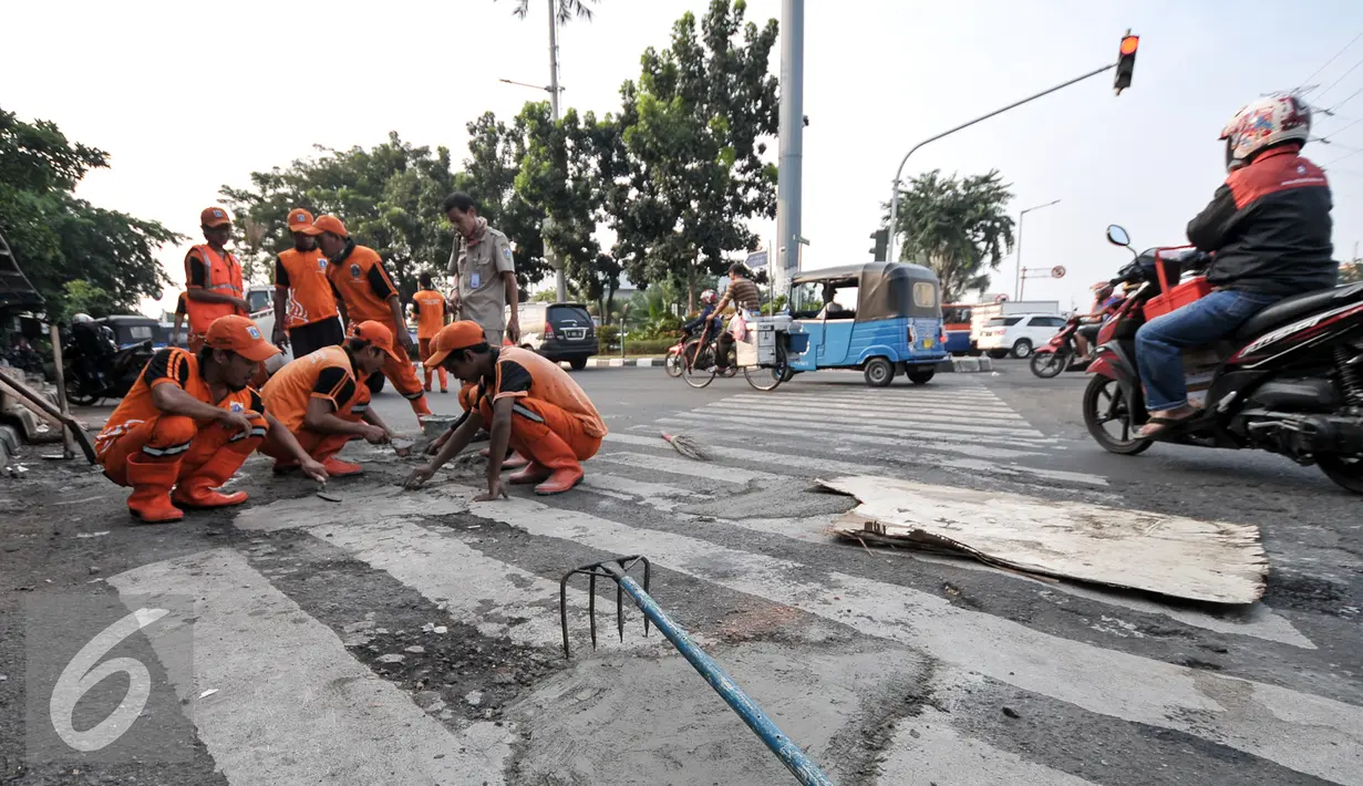 Jalan berlubang di kawasan Senen sedang ditambal oleh petugas, Jakarta, Selasa (26/7). Penambalan jalan berlubang ini bertujuan untuk kenyamanan pengguna jalan yang melintas. (Liputan6.com/Yoppy Renato)