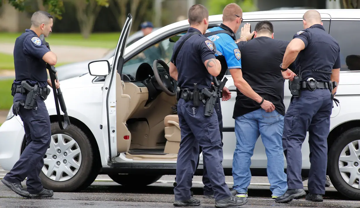 Petugas memeriksa warga di dekat lokasi penembakan petugas kepolisian di Baton Rouge, Louisiana, AS, Minggu (17/7). Insiden terjadi setelah seorang pria bersenjata, bertopeng dan berpakaian hitam melepas tembakan dengan senapan serbu (REUTERS/Joe Penney)