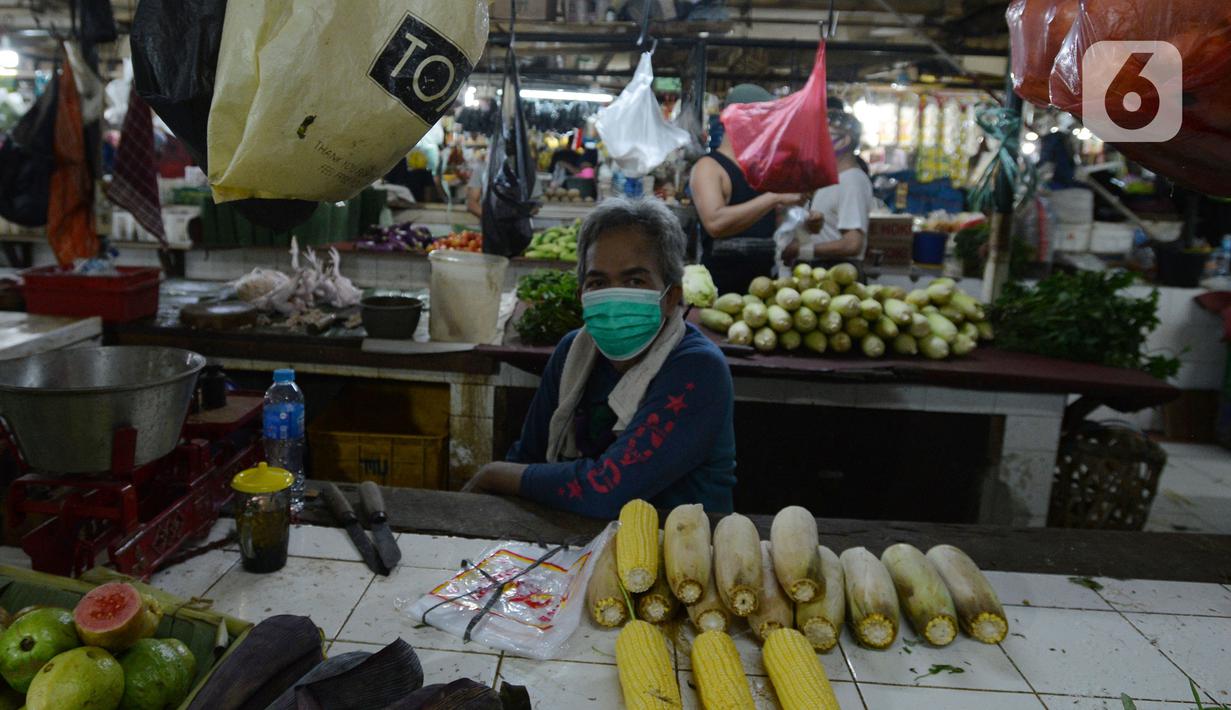 Pedagang mengenakan masker yang dibagikan petugas Polres Jakarta Timur selama sosialisasi di Pasar Palmeriam, Matraman, Selasa (9/2/2021). Kegiatan tersebut sebagai upaya meningkatkan kesadaran akan pentingnya penerapan protokol kesehatan untuk menekan penyebaran Covid-19. (merdeka.com/Imam Buhori)