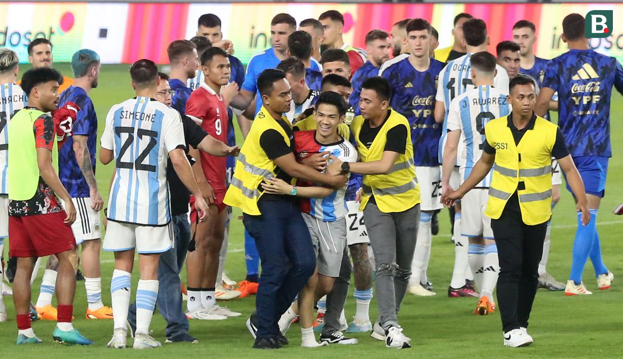 Petugas keamanan berhasil mengamankan seorang suporter yang masuk kedalam lapangan setelah laga FIFA Matchday antara Timnas Indonesia Vs Timnas Argentina di Stadion Utama Gelora Bung Karno (SUGBK), Senayan, Jakarta, Senin (19/06/2023). (Bola.com/M Iqbal Ichsan)