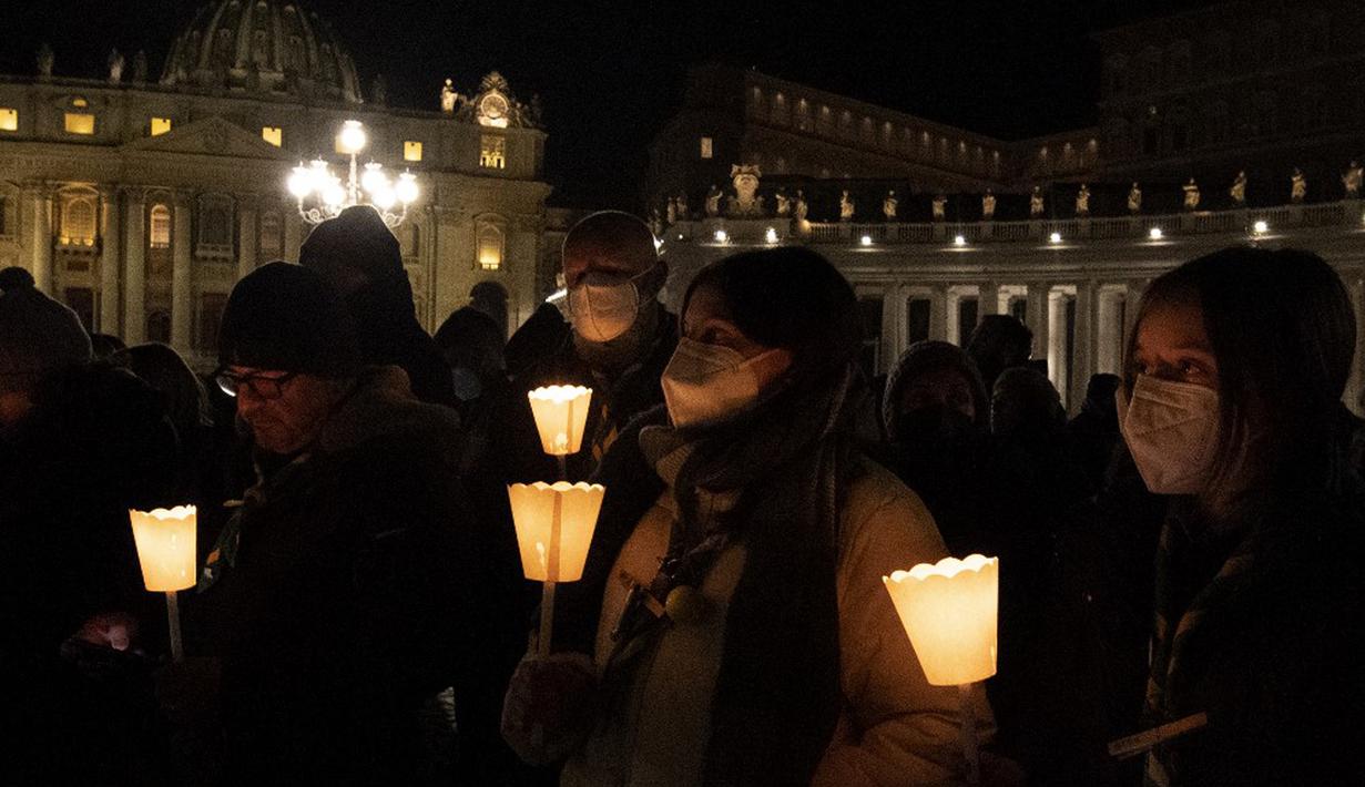 Orang-orang yang percaya memegang lilin saat berdoa untuk perdamaian Ukraina di Lapangan Santo Petrus, Vatikan, 2 Maret 2022. (Tiziana FABI/AFP)