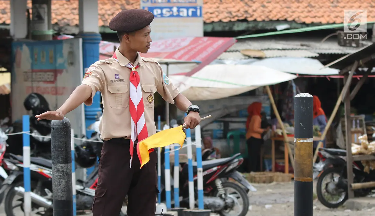 Anggota Pramuka membantu mengatur lalu lintas di jalur mudik kawasan pasar Surodadi, Tegal  Jawa Tengah, Senin (3/6/2019). Puluhan anggota Pramuka  membantu polisi mengatur lalu lintas selama arus mudik maupun arus balik. (Liputan6.com/Herman Zakharia)