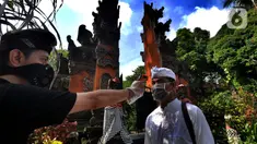 Petugas memeriksa suhu tubuh pengurus Pura Amerta Jati menjelang persiapan Hari Raya Nyepi Saka 1942 di Cinere, Depok, Selasa (24/3/2020). Rangkaian perayaan Nyepi di sejumlah pura hanya akan dilakukan oleh panitia dalam jumlah terbatas untuk mencegah penyebaran Covid-19. (merdeka.com/Arie Basuki)