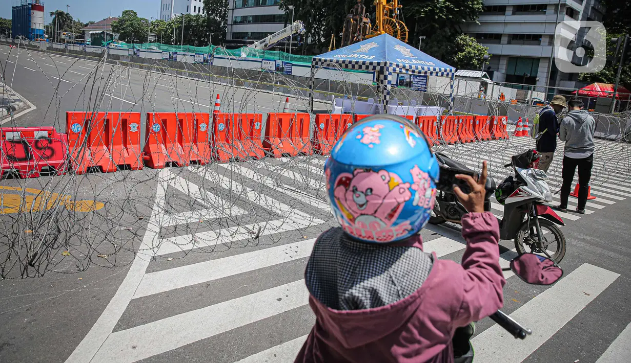 Warga mengambil gambar kawat berduri di kawasan Jalan MH Thamrin, Jakarta, Kamis (2/12/2021). Polda Metro Jaya memasang barikade di sejumlah titik menuju kawasan Patung Kuda-Monumen Nasional (Monas) Jakarta Pusat guna mengantisipasi kerumunan massa aksi Reuni 212. (Liputan6.com/Faizal Fanani)
