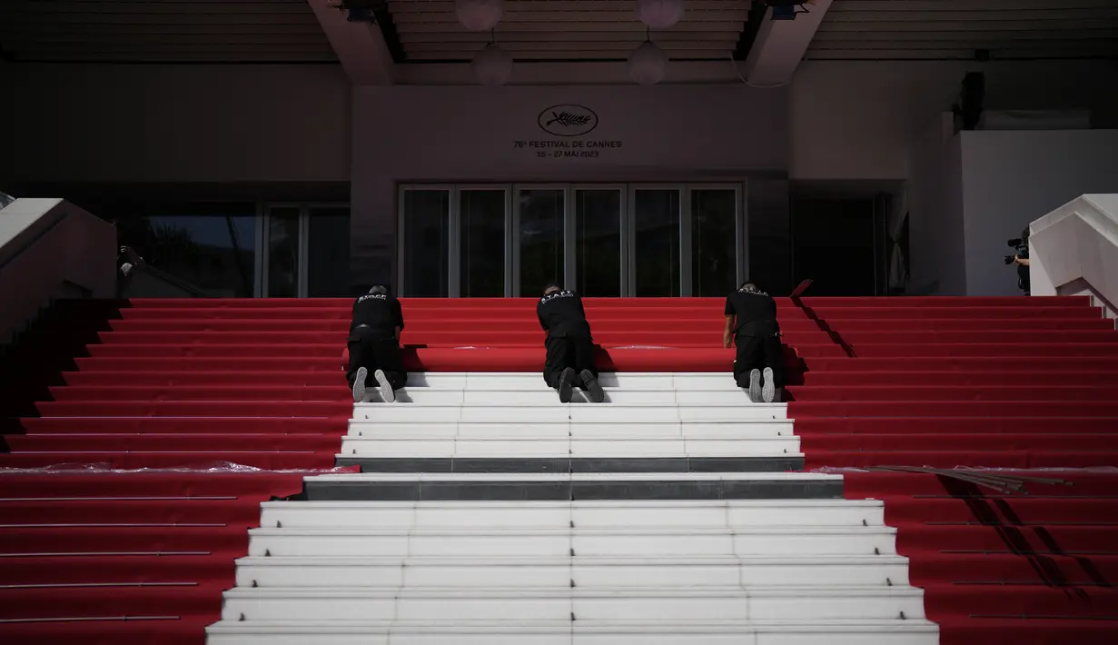 Para pekerja menggelar karpet merah festival film internasional ke-76, Cannes, Prancis selatan, Selasa (16/5/2023). (AP Photo/Daniel Cole)