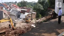 Warga menyaksikan rumah yang hancur tertimpa tanah longsor di Perumahan Nerada Estate Ciputat, Tangerang Selatan, Sabtu (12/6/2021). Tidak ada korban jiwa dalam peristiwa longsor yang menimpa sejumlah rumah akibat hujan deras yang terus menerus di kawasan tersebut. (Liputan6.com/Angga Yuniar)
