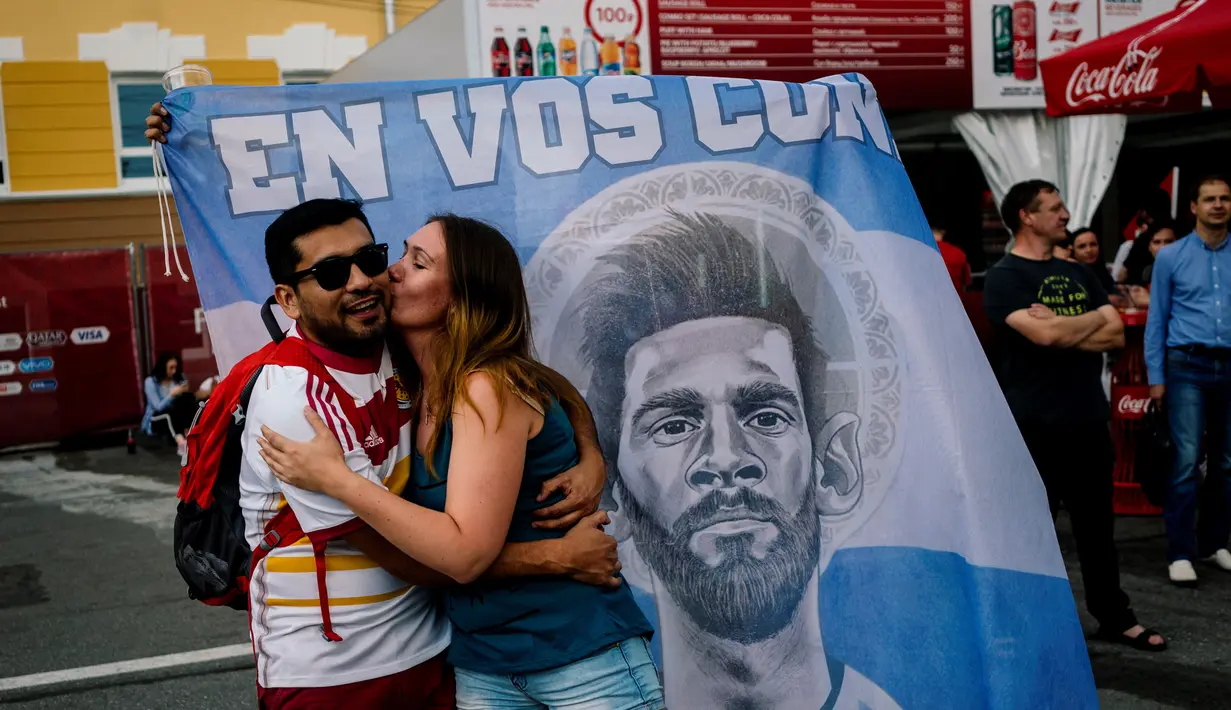 Seorang suporter Argentina mencium kekasihnya saat berada di jalanan Nizhny Novgorod, Selasa (19/6/2018). Cerita sepenggal kisah romantis saat Piala Dunia 2018 Rusia. (AFP/Dimitar Dilkoff)