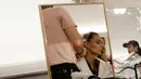 Seorang model saat ditata rambutnya di belakang panggung sebelum presentasi busana koleksi Spring-Summer 2018 Versace di Milan, Italia (17/6). Presentasi Spring-Summer 2018 Versace merupakan bagian dari Milan Fashion Week. (AP Photo/Antonio Calanni)
