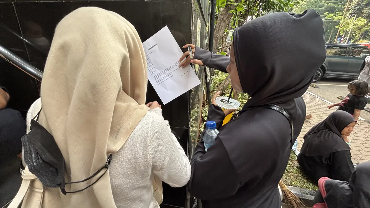 Momen orang tua pelajar menulis surat pernyataan saat hendak menjemput anaknya yang ditangkap pihak kepolisian di Polda Metro Jaya akibat diduga terlibat kericuhan saat demo di DPR